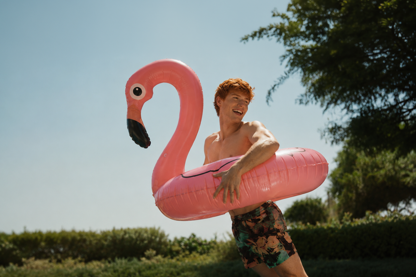 Red-haired gender-neutral twink with muscles outdoors in summer with healthy glowing skin, representing natural skincare, hydration and seasonal skin protection