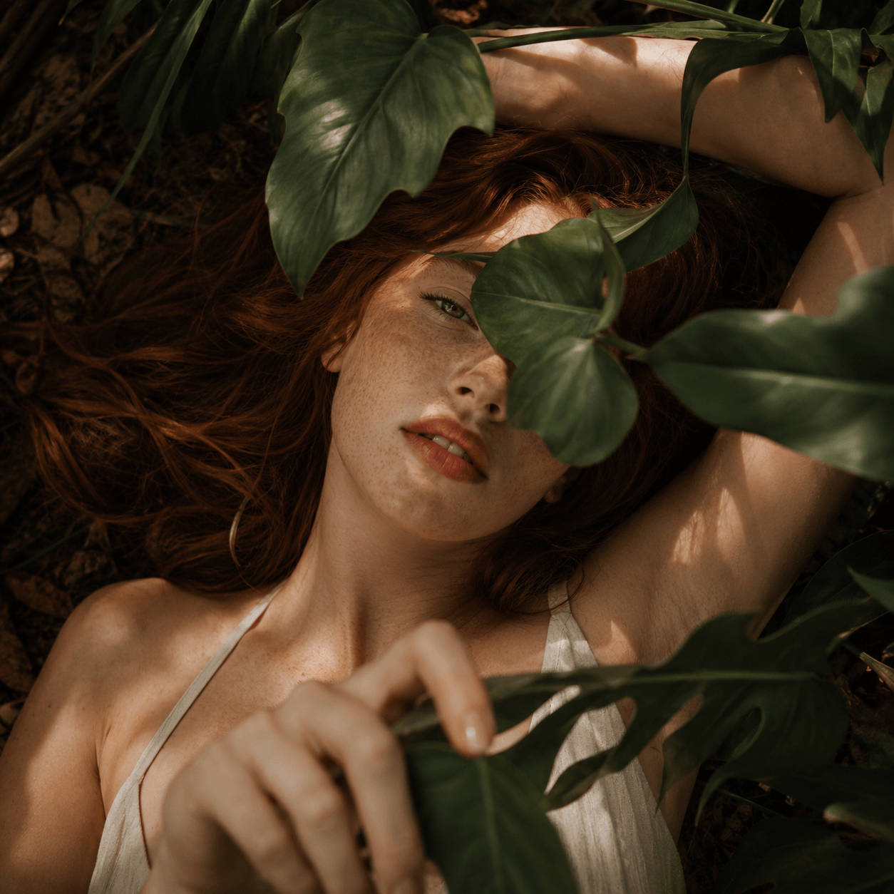 Woman lying among green leaves with a natural, earthy background Suvera Skincare, natural skincare