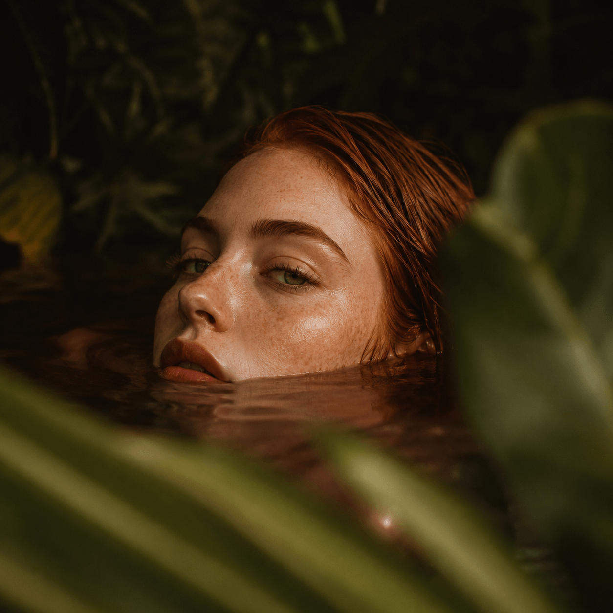 Woman with red hair partially submerged in water surrounded by green foliage Suvera Skincare, modern skincare