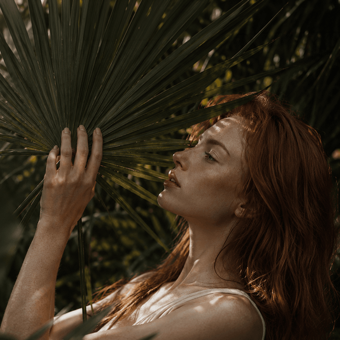 Woman holding a palm leaf in a natural setting Suvera Skincare, natural vegan skincare