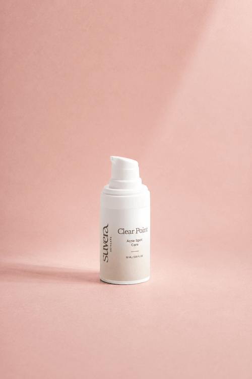 A white pump bottle of Suvea Clear Skin Care Clear Skin Cream standing on a dusty pink background with soft diagonal shadows.