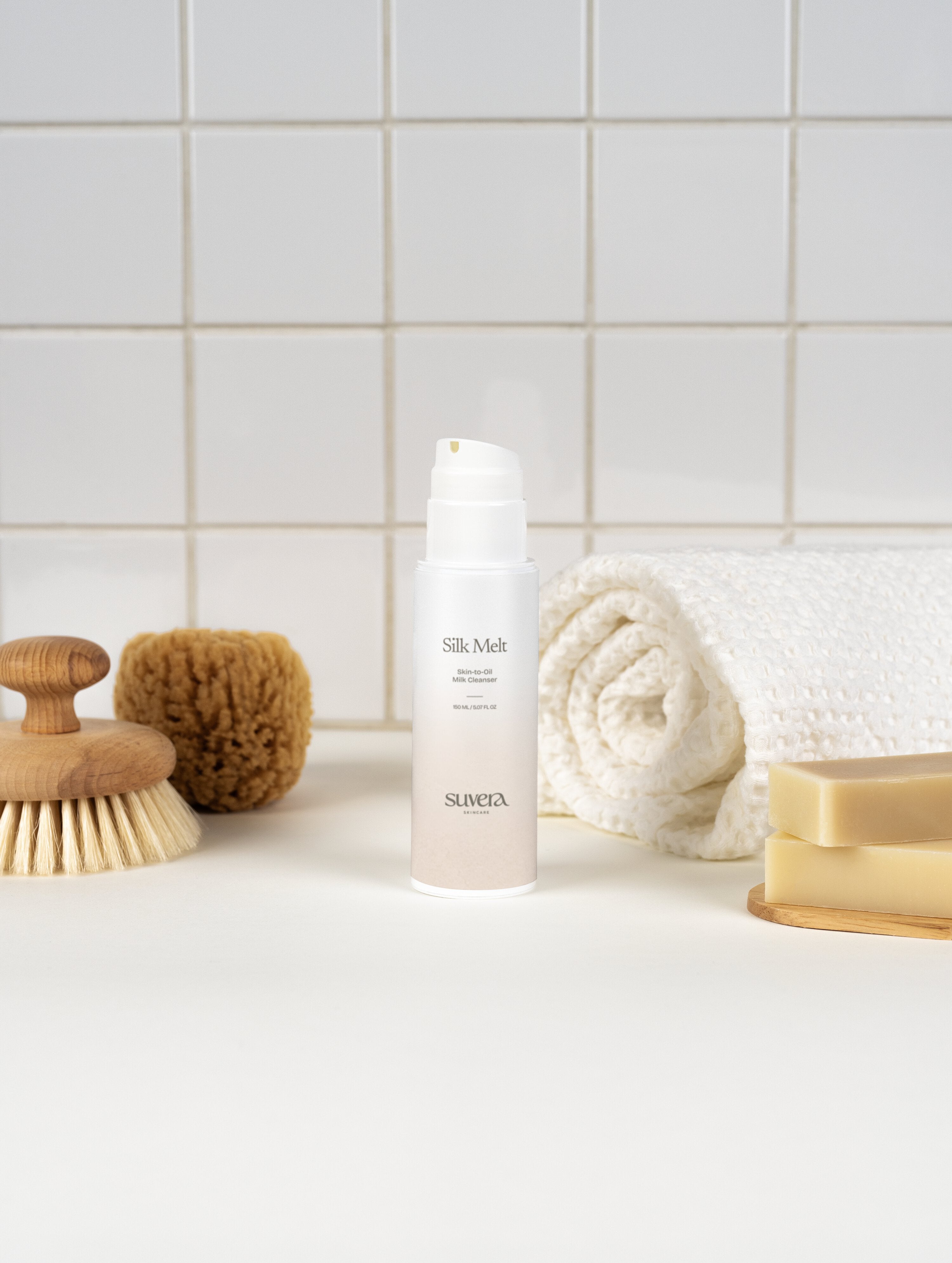 Silk Mea bottle on a bathroom counter with a towel, soap, and scrubber in the background. Suvera Skincare, skin ritual