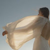 Woman in cream colored dress floating in the wind with bright sky Suvera Skincare, modern skincare ritual, vegan beauty