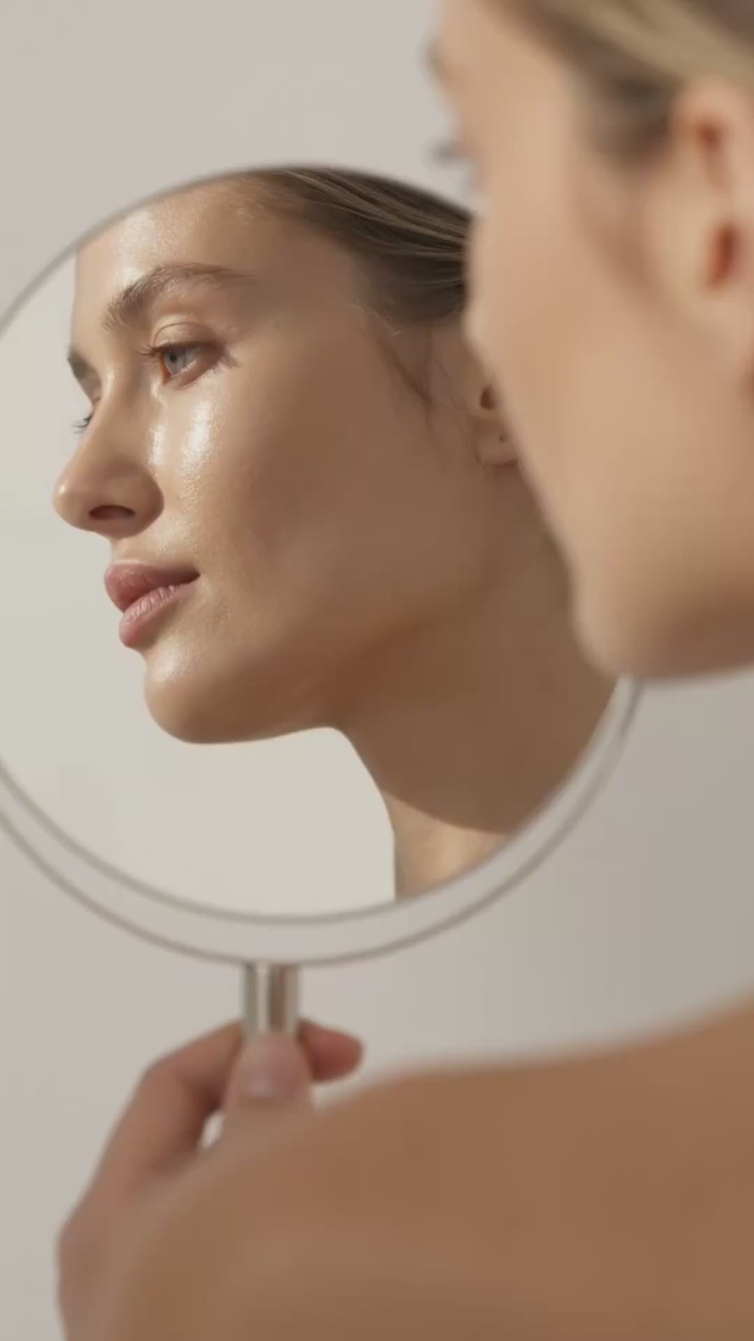 Scene where young woman with glowing skin looks into the mirror Suvera Skincare, anti-acne skincare, gentle skincare