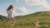 Woman peacefully running through hills with grass Suvera Skincare, natural vegan skincare, luxury skincare